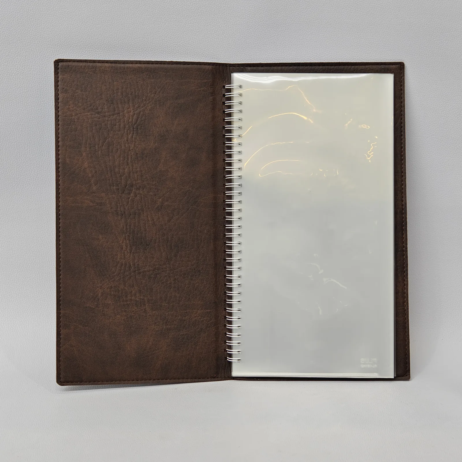 Interior view showing the brown leather lining and a spiral-bound clear plastic sleeve.