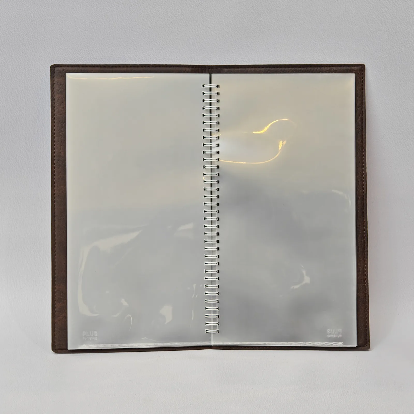 Open menu cover displaying multiple clear plastic sleeves held by a white spiral binder.