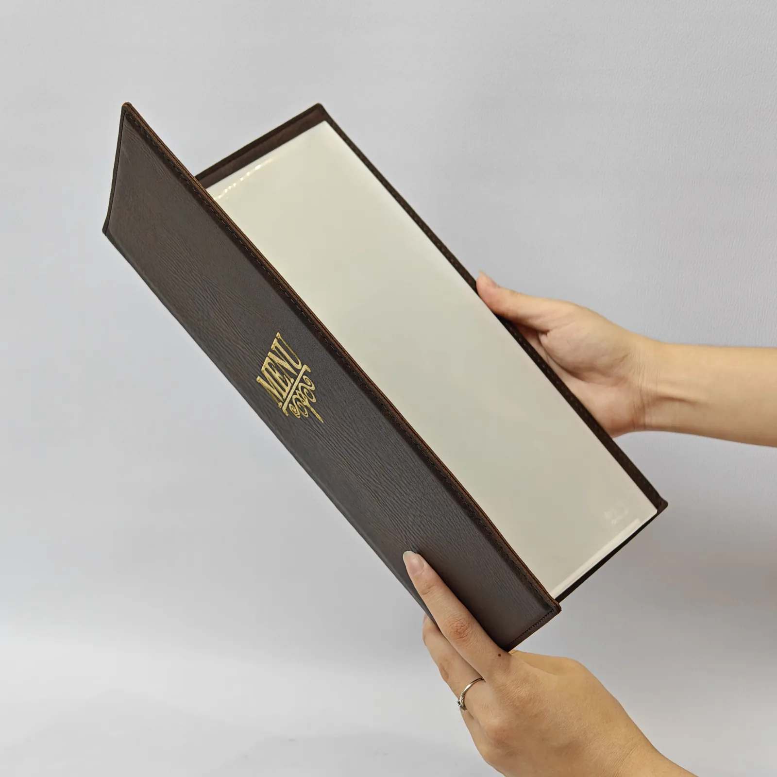 A person holding the open menu cover showing the clear internal sleeves.