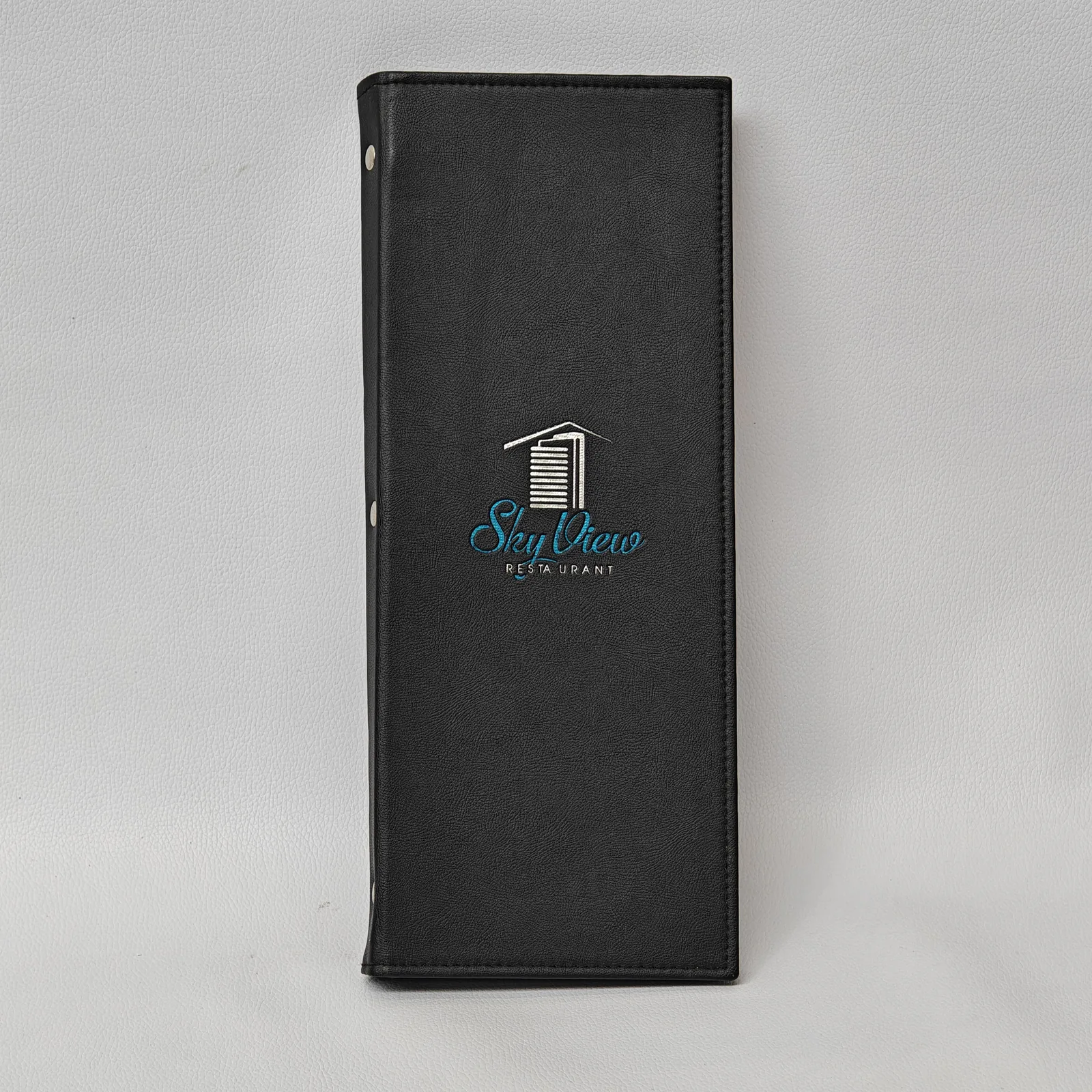 Tall black leather menu cover with a silver and blue logo and visible screw post binding on the spine.