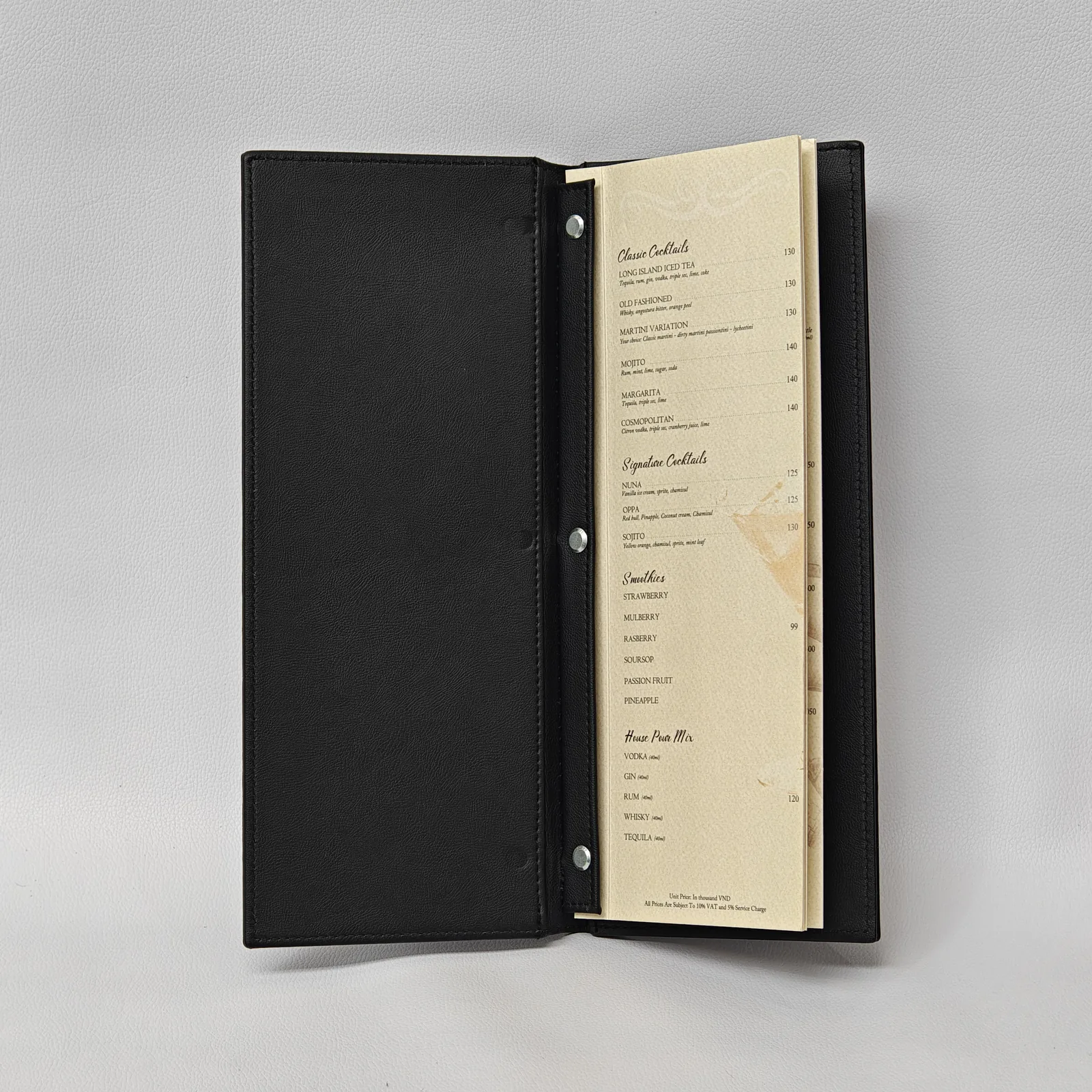 Open black leather menu cover showing paper menu pages secured by three silver screw posts.