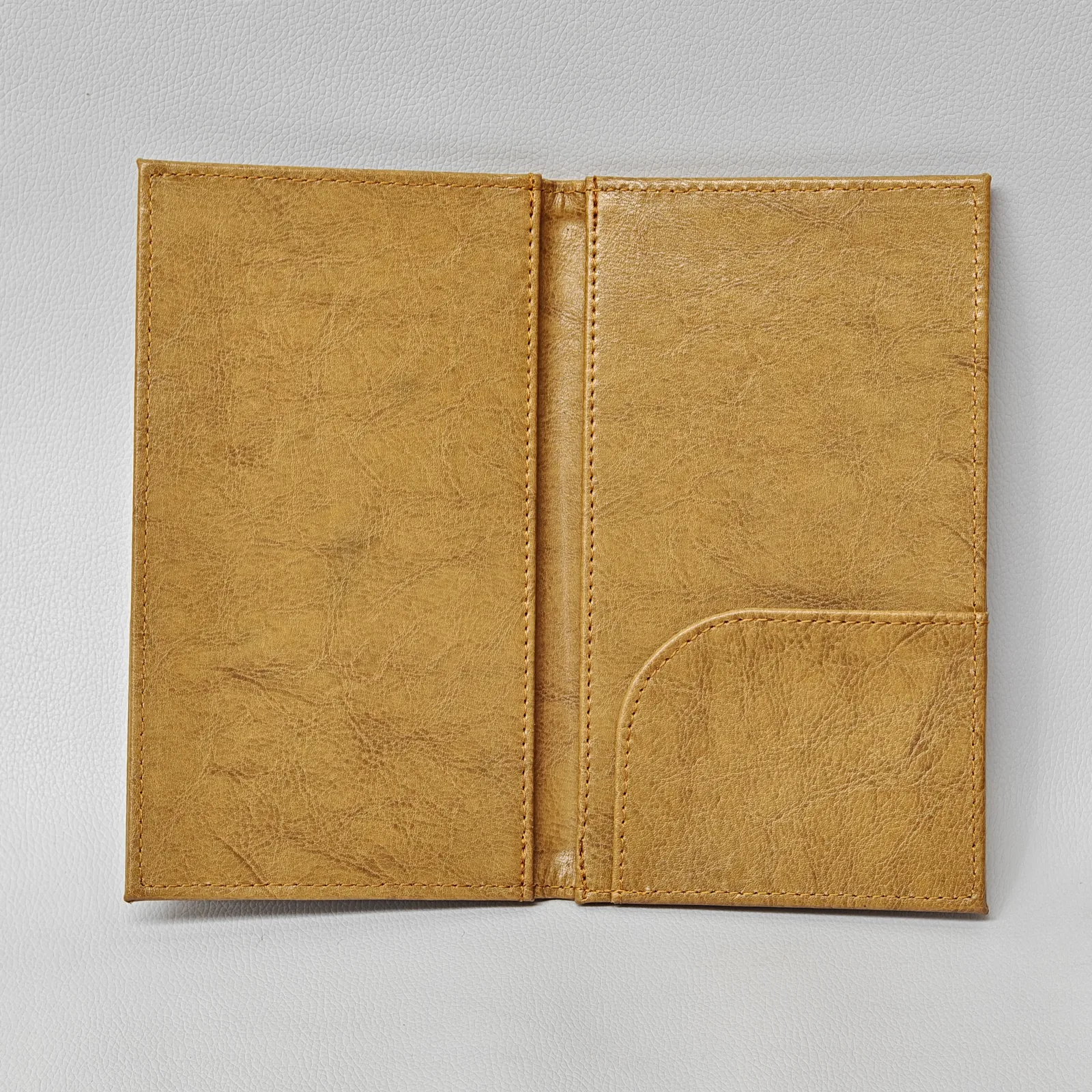 Open tan leather check presenter showing a curved pocket on the right side and matching stitching.