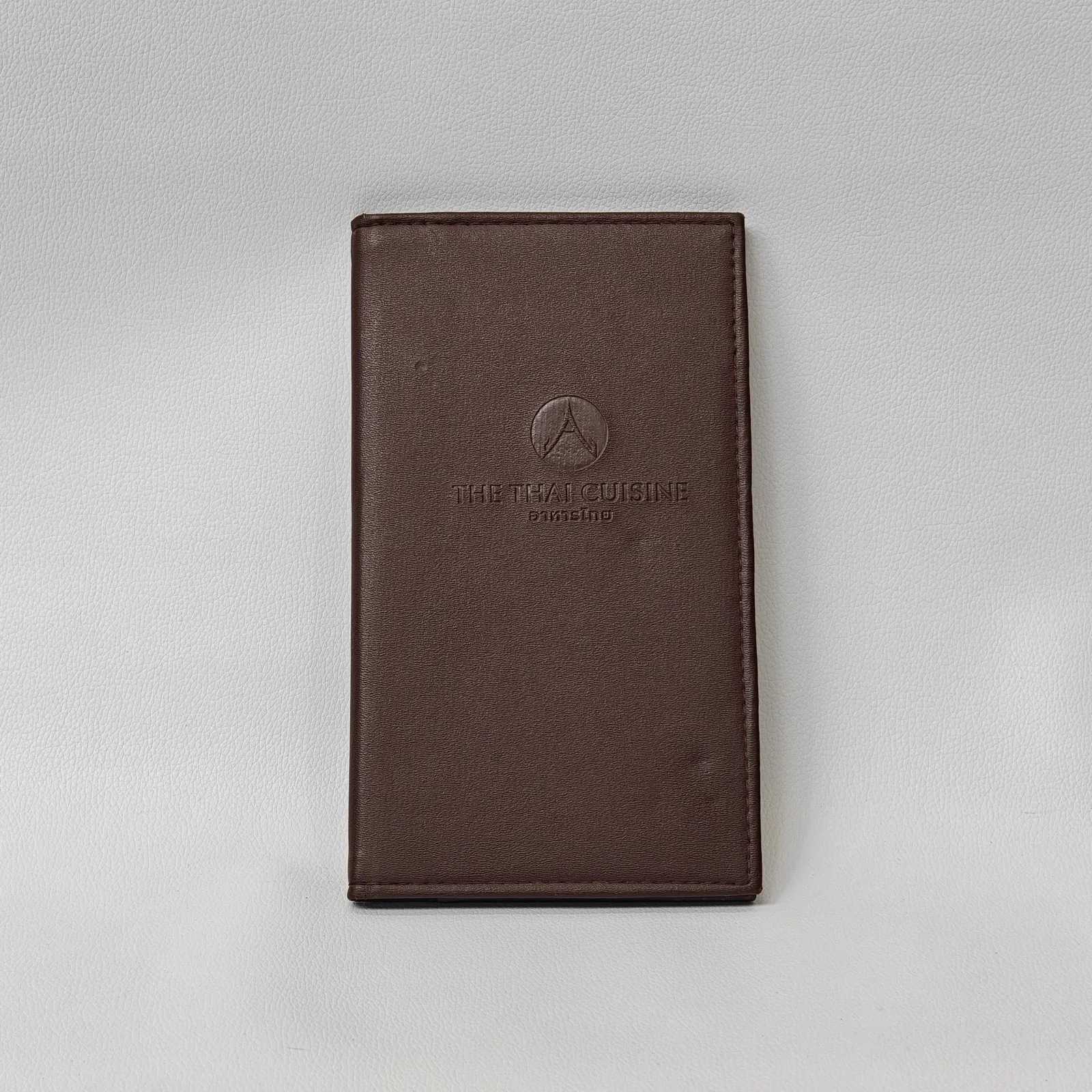 Taupe leather menu cover with embossed Thai temple and restaurant name